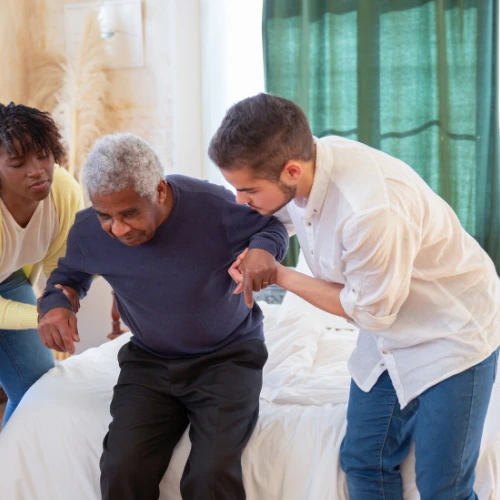 caregivers helping a man walk in a nursing home
