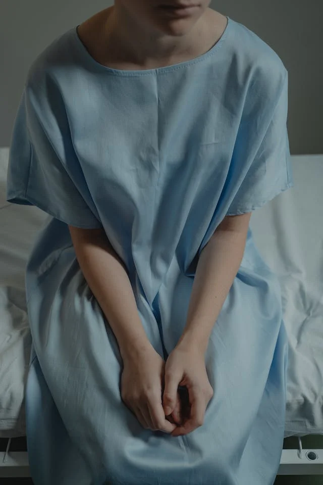 Person in Hospital Gown Sitting on the Hospital Bed