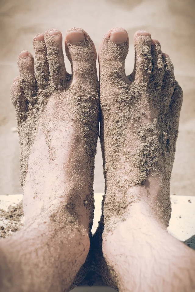 closeup photo of person's feet covered with sand